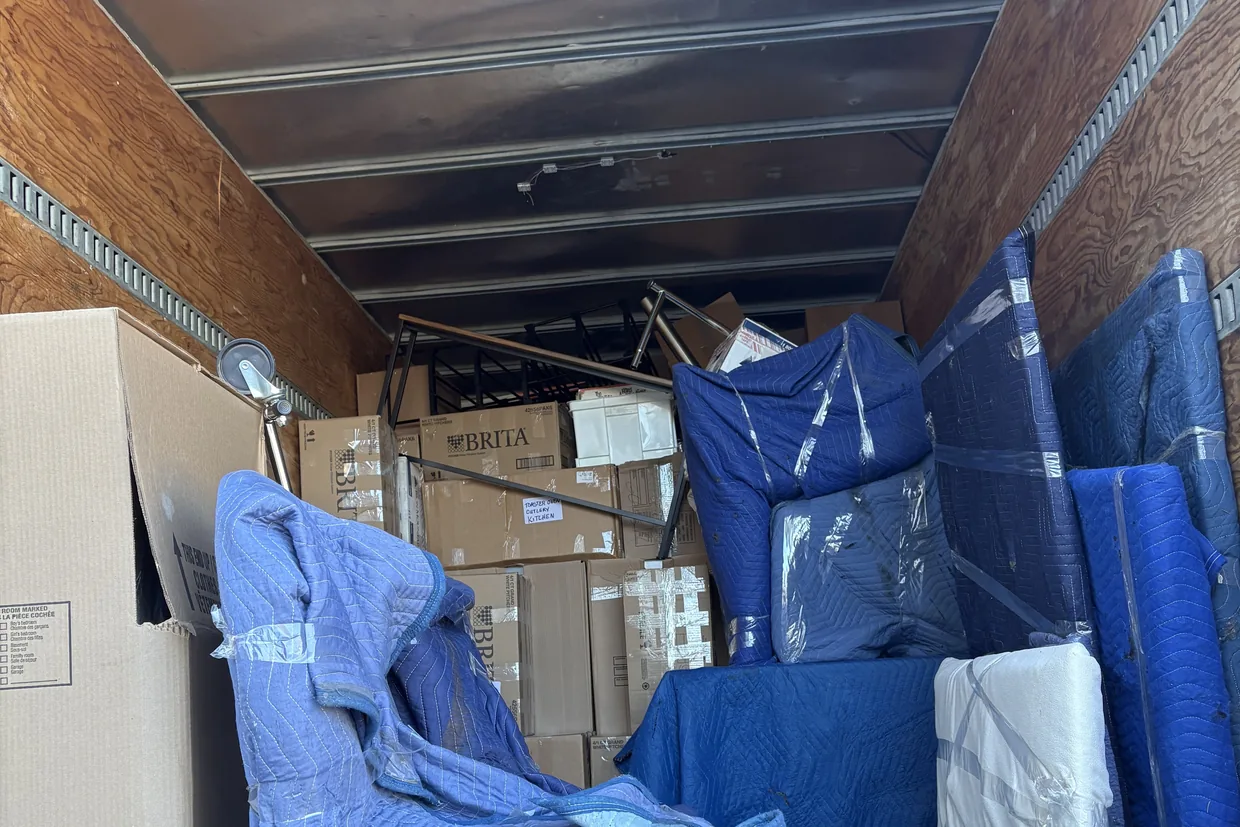 Blanket-wrapped furniture and boxes stacked tight inside a Motion Transport moving truck