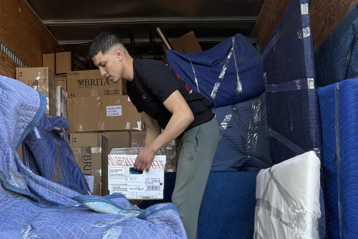 Motion Transport crew member loading a box into the moving truck alongside blanket-wrapped furniture