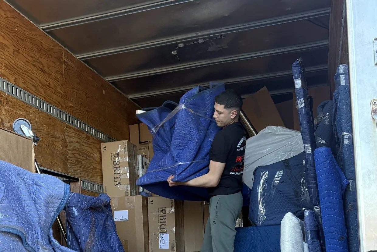 Motion Transport crew member loading a wrapped mattress at the tail of the moving truck