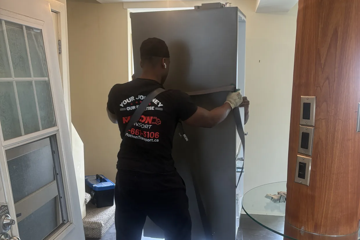 Motion Transport crew member securing a refrigerator with a moving strap during a household move
