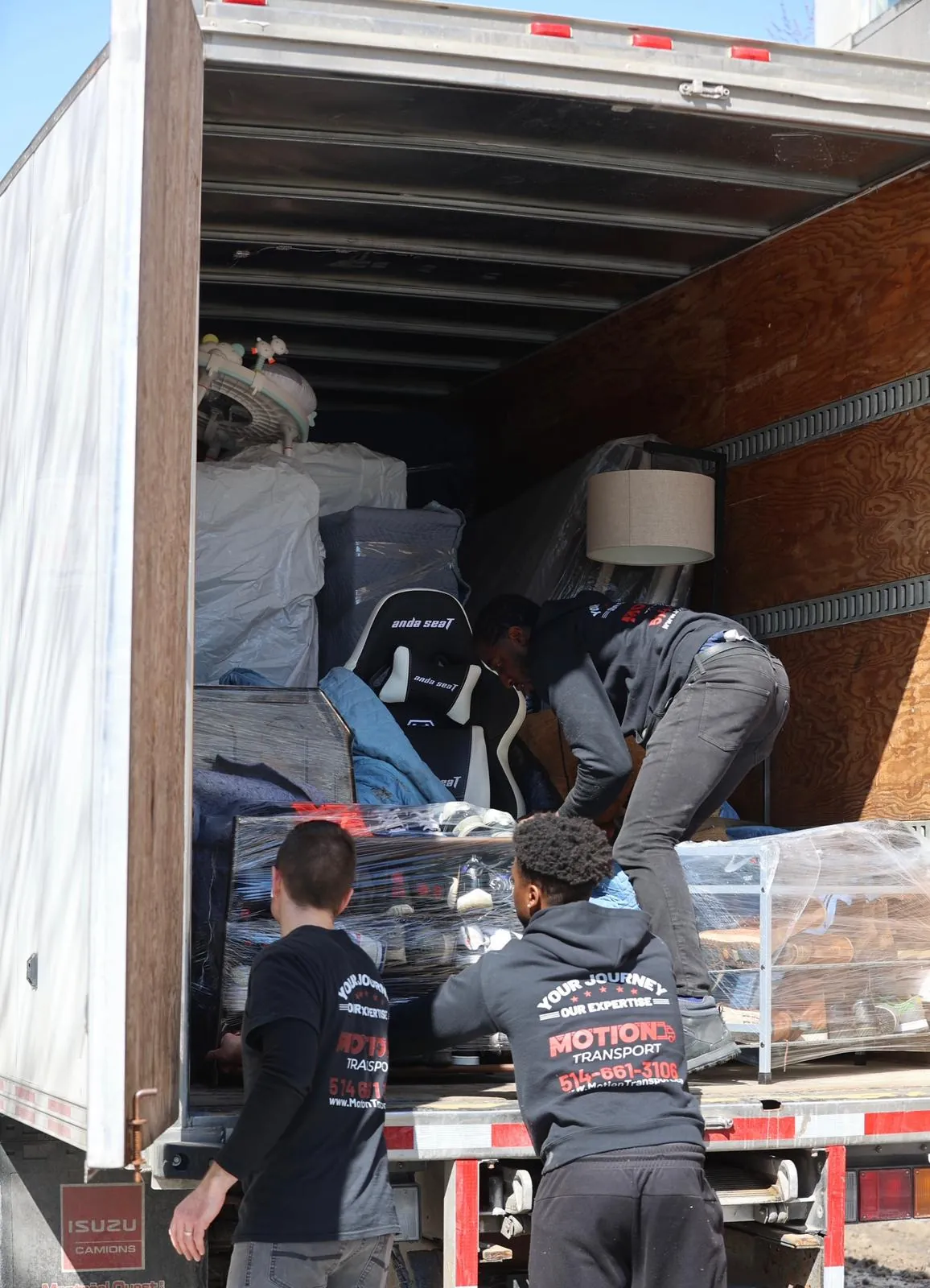 Two Motion Transport team members loading furniture into the moving truck cab
